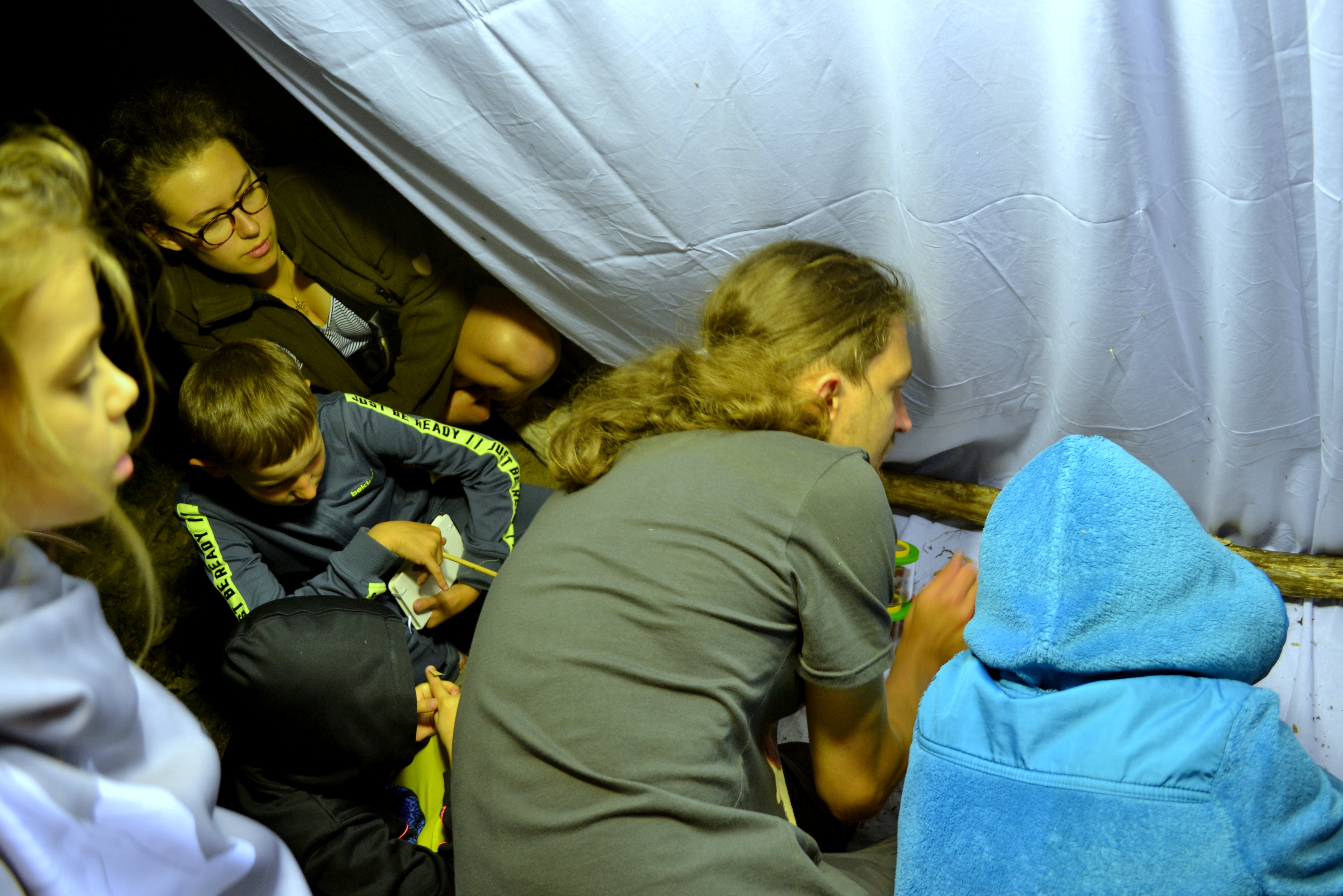 Fot. Zdjęcie przedstawia Przemysława Wieczorka oraz uczestników NOCy CIEMnej podczas obserwacji owadów przy ekranie. Fot. P. Kaźmierczak